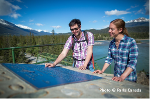 Visitors reading the Athabasca Canadian Heritage River designation plaque in Jasper National Park, Alberta.