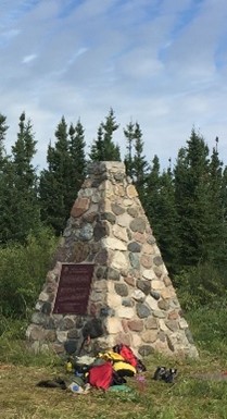 Un monument en forme de pyramide faite de pierres. Une plaque commémorative est apposée sur un des côtés du monument.