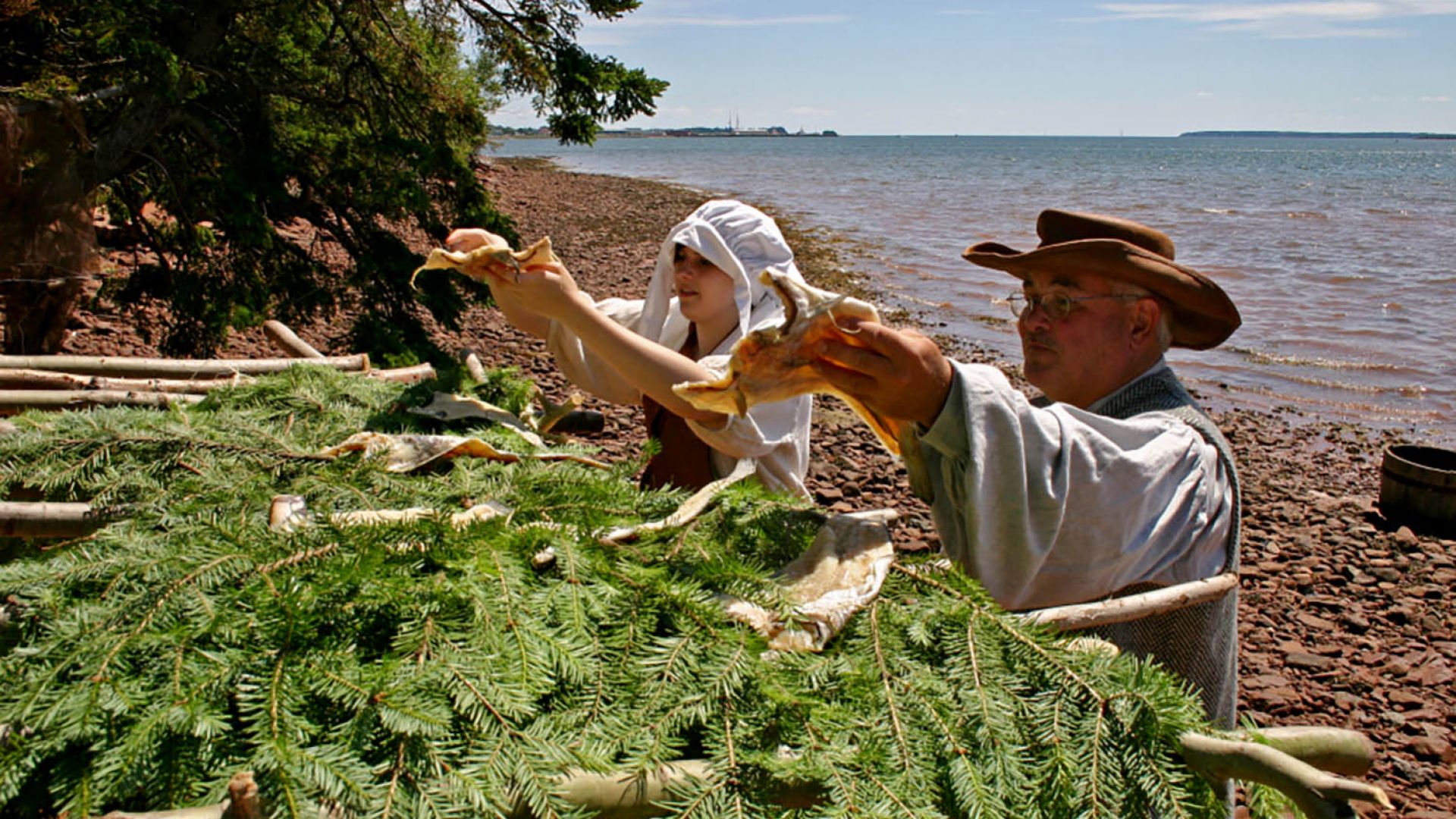 Deux volontaires montrant comment les colons séchaient la morue pour l’exporter en Europe de 1732 à 1745, sur la rivière Montague. Les rivières Montague, Brudenell et Cardigan forment le bassin Three Rivers du patrimoine canadien