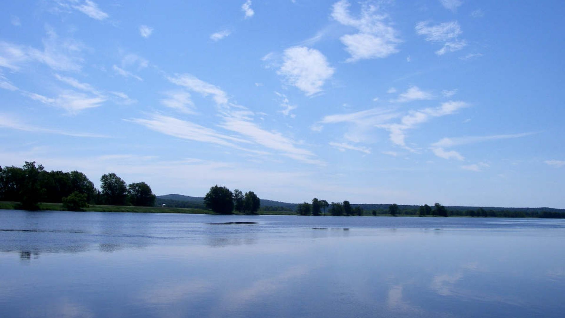 The calm waters of the St. John River reflect the wispy clouds in the blue sky above.