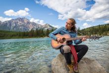 Personne jouant de la guitare au bord de la rivière Athabasca dans le parc national Jasper