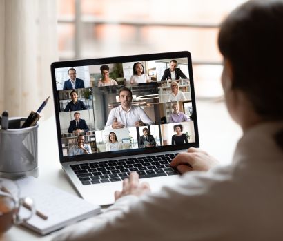 Vue par-dessus l'épaule d'un écran d'ordinateur montrant une vidéoconférence.