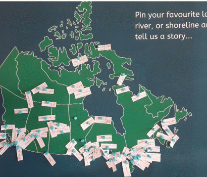 Carte du Canada sur laquelle sont épinglés des morceaux de papier indiquant les noms des plans d'eau. La légende sur la carte indique: « Épinglez votre lac, votre rivière ou votre rivage préféré et racontez-nous une histoire... ».