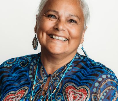 Portrait souriant de l'aînée Sheila De Corte sous un éclairage de studio.