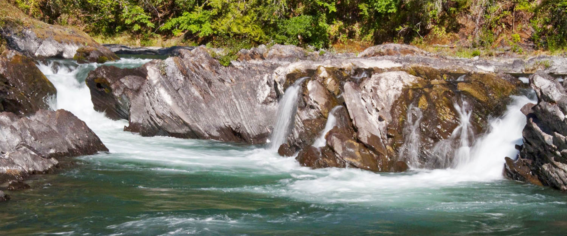Water from the Cowichan River rushes over weathered rocks
