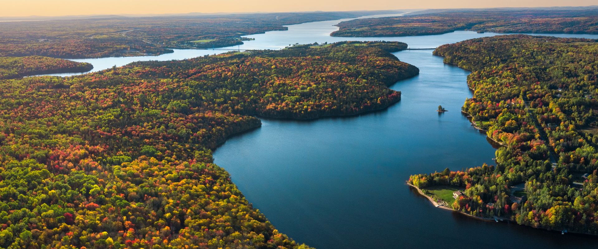 Wolastoq/St John River flowing through colourful deciduous forests in the fall.